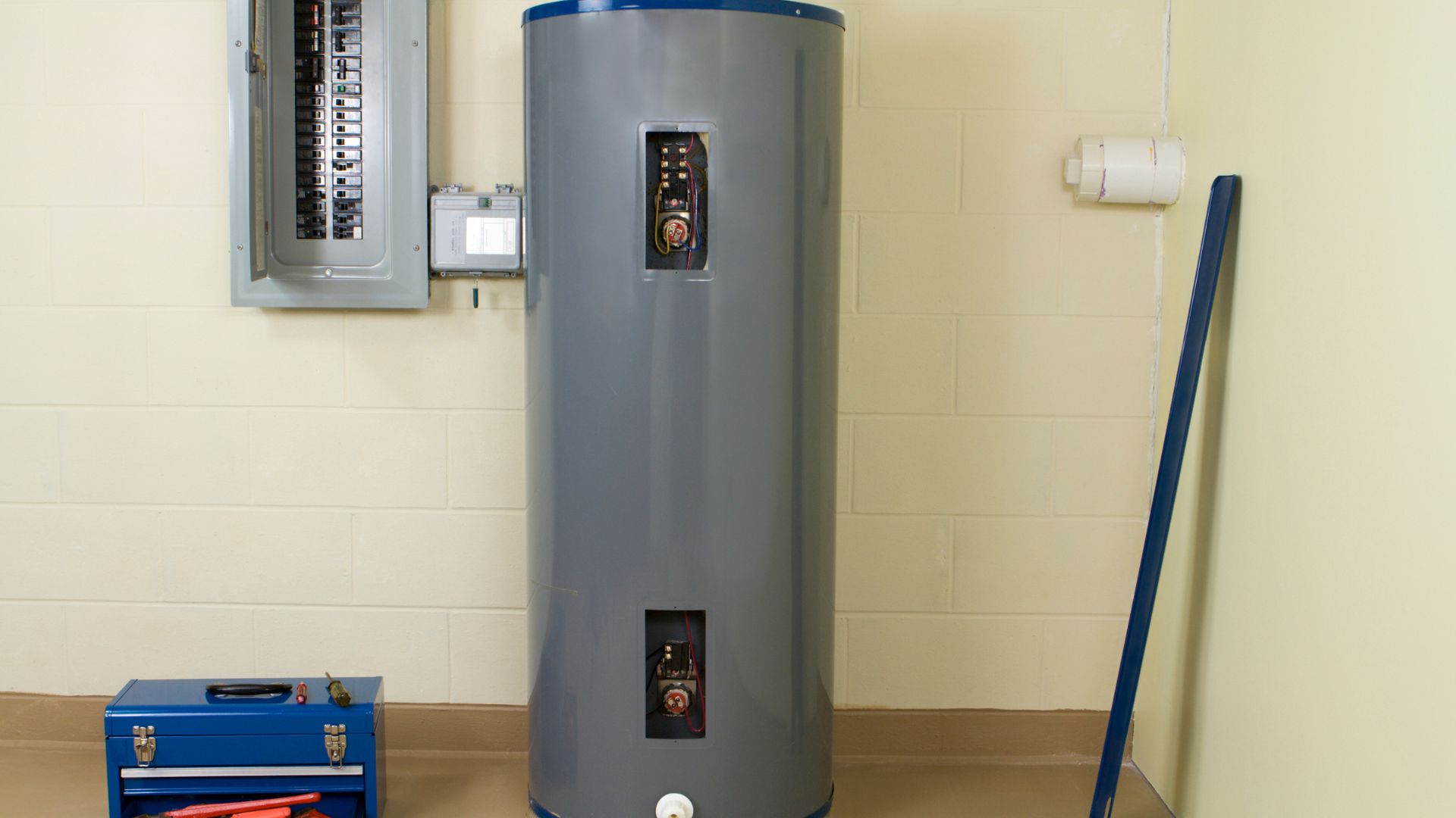 Large gray water heater next to electrical panel and blue toolbox