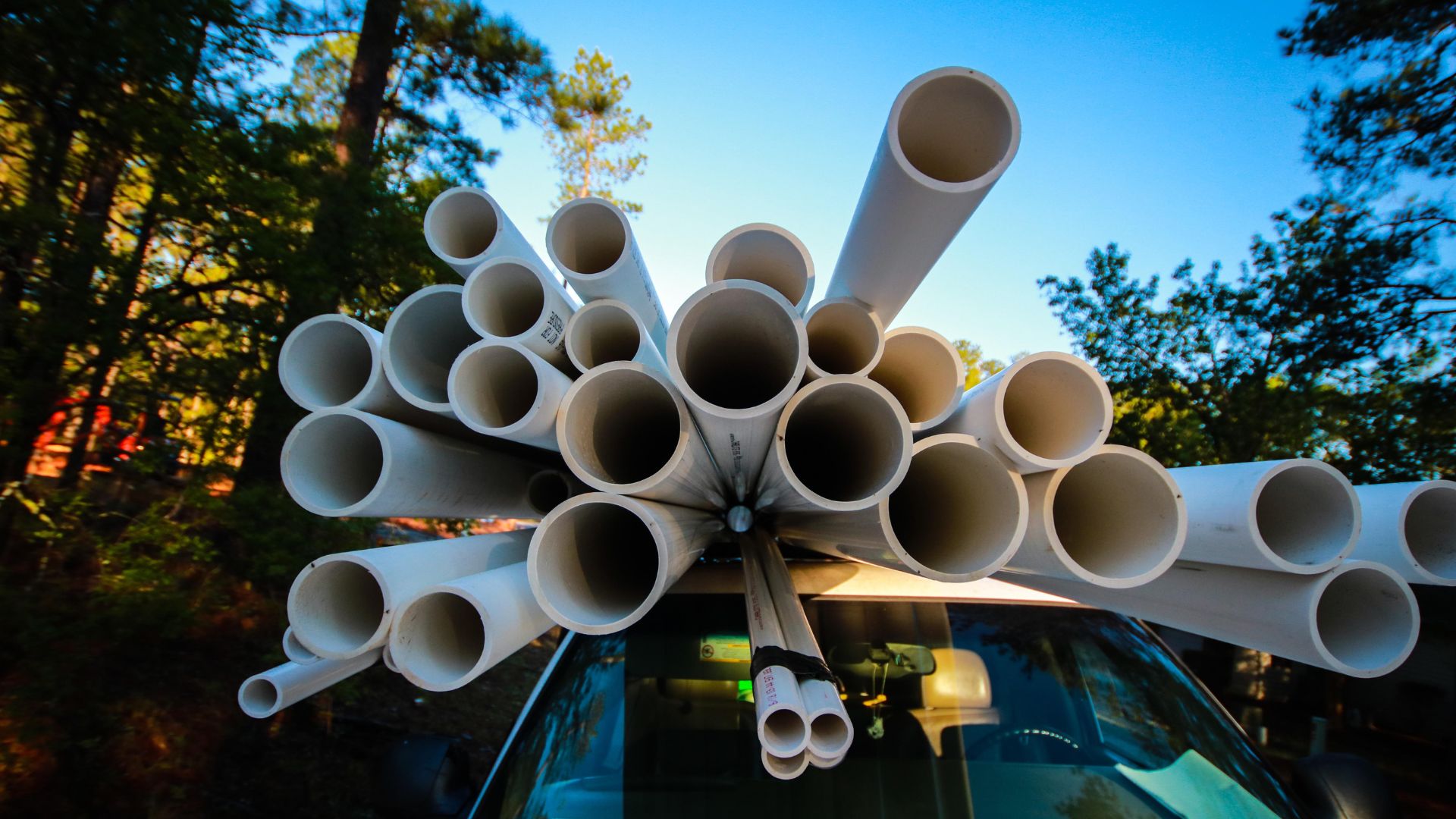 White PVC pipes stacked and bundled on top of a blue vehicle