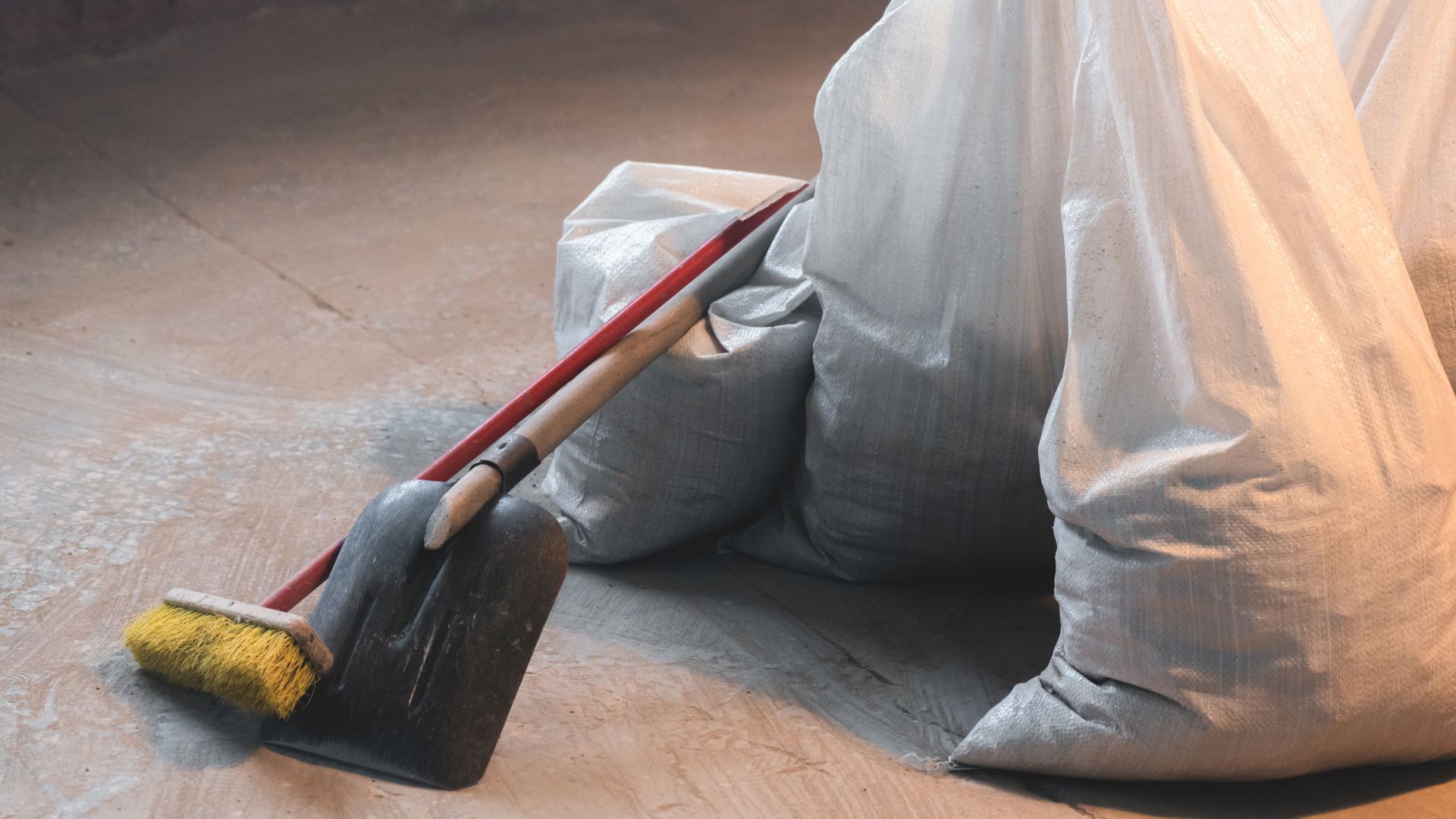 Dustpan and brush with gray cleaning bags on wooden floor