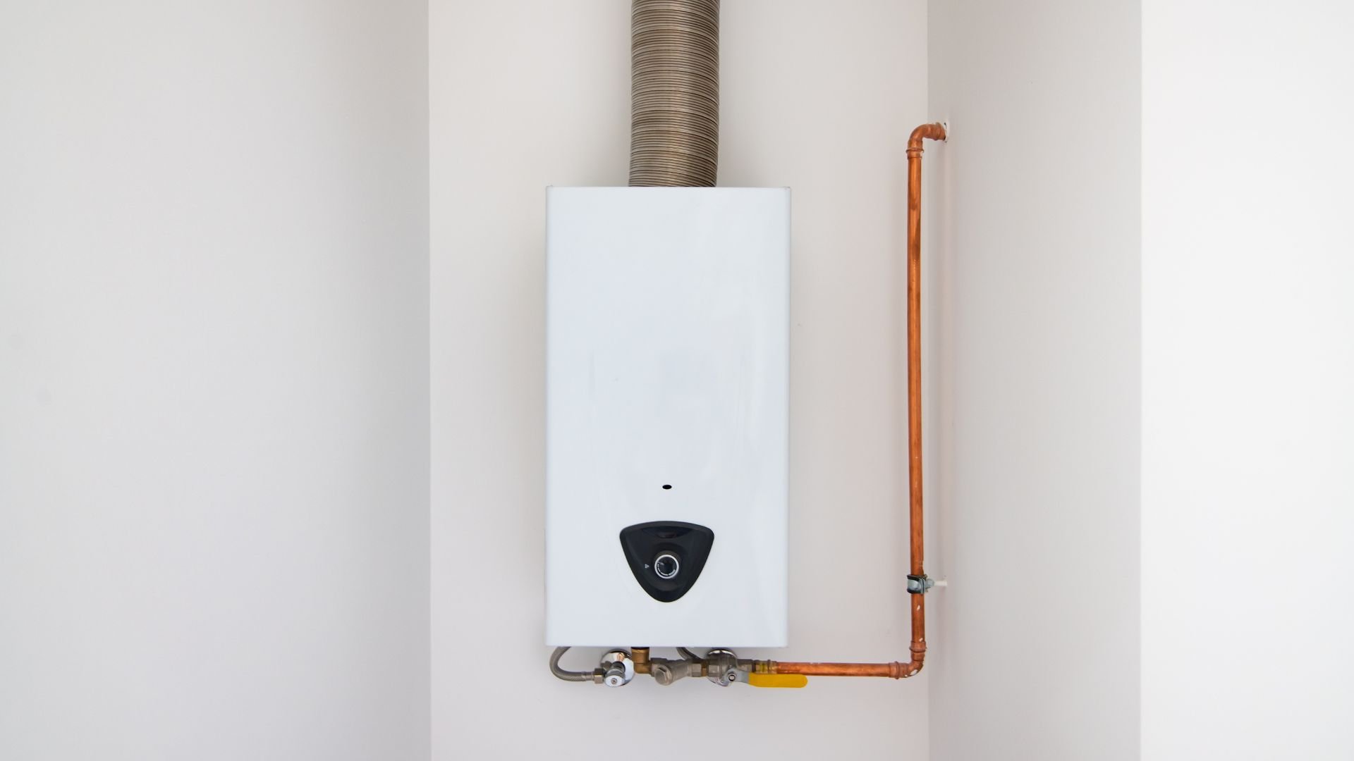 White tankless water heater mounted on wall with copper pipes