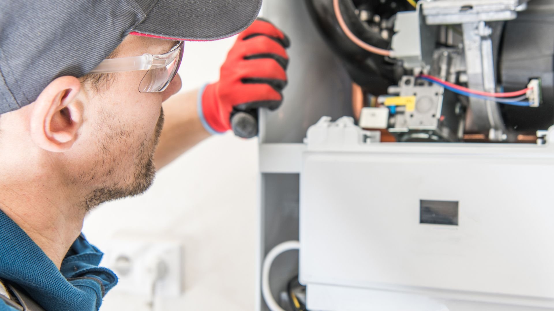 Technician in safety glasses and red gloves inspecting electrical equipment